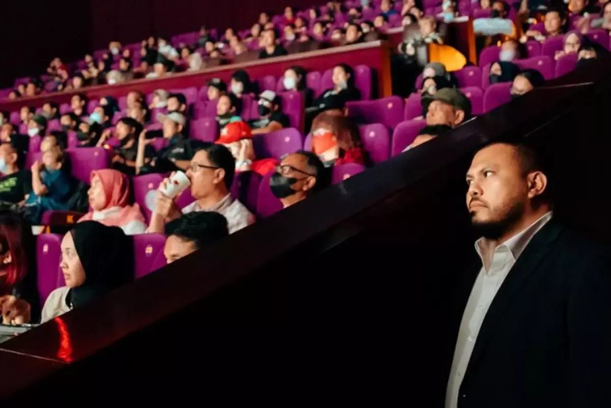 Joko Anwar yang sedang menyaksikan film di pinggir bangku penonton bioskop.