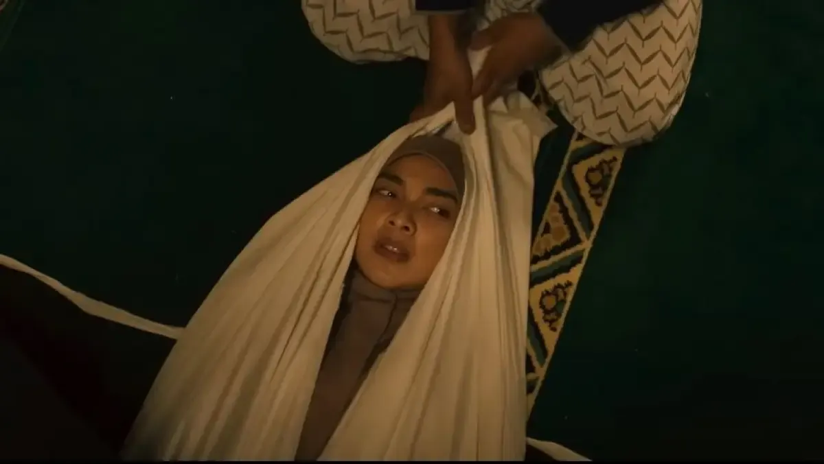 Tika Bravani memerankan adegan menggunakan kain kafan (Sumber : Tangkap Layar/Youtube Cinema 21)