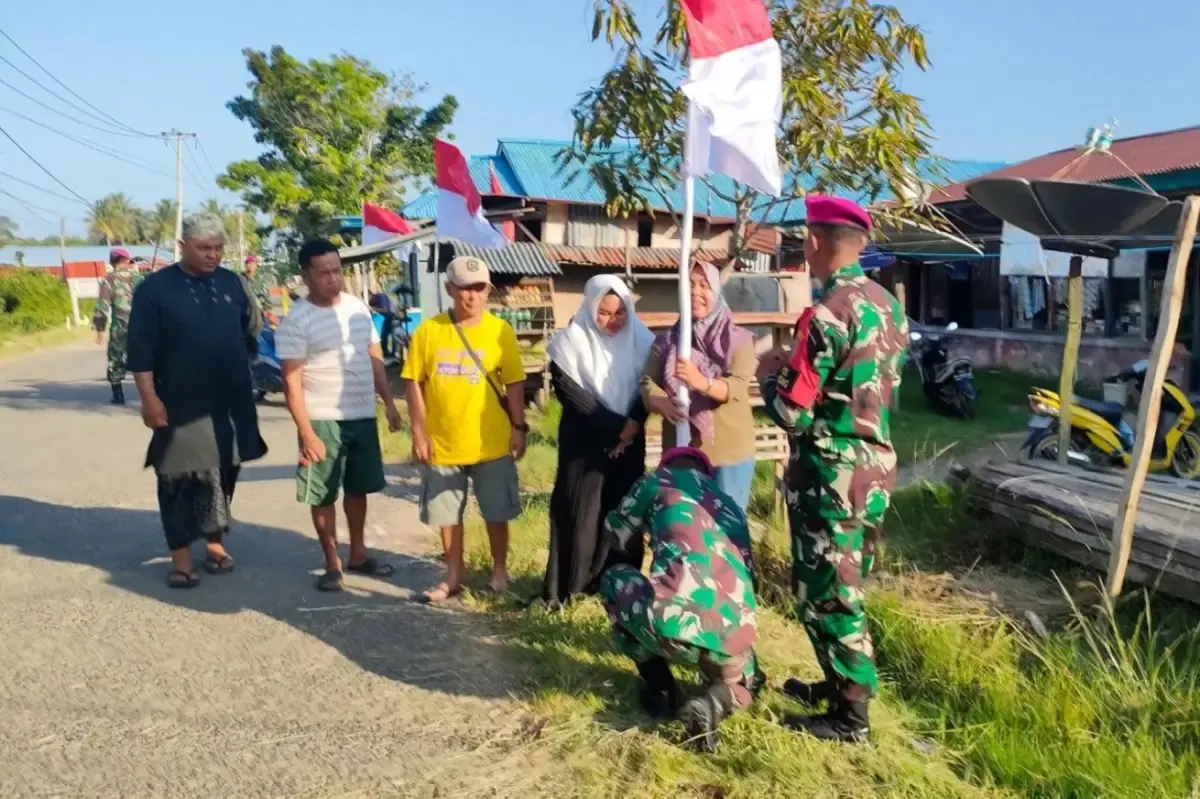 Proses pemasangan bendera merah putih di depan rumah warga. (Sumber : Twitter/@marinir_tni_al)