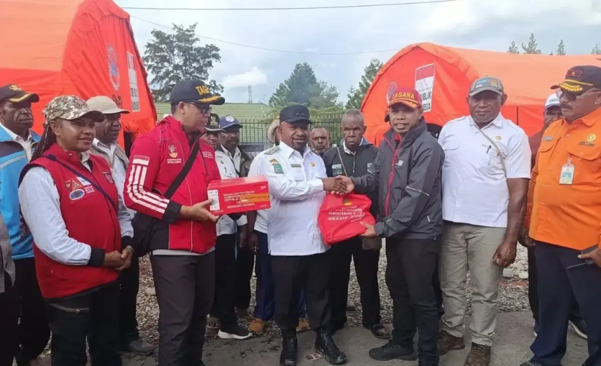 Perwakilan Kemensos RI Roberto Koibor (kanan) ketika menyerahkan secara simbolis bantuan yang diterima oleh Wabup Jayawijaya Ronny Elopere di Posko Satgas Tanggap Darurat Bencana Banjir dan Longsor Kabupaten Jayawijaya, Rabu (30/4/2025). (Sumber: Antara)