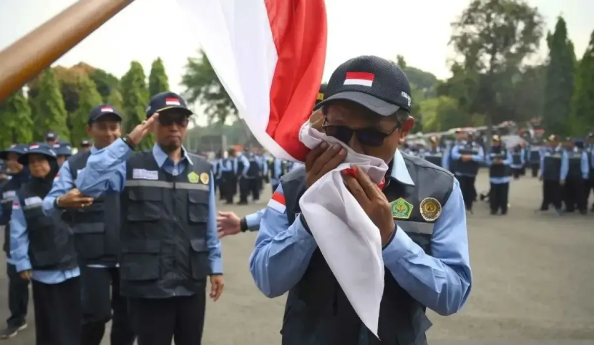 Petugas Penyelenggara Ibadah Haji (PPIH) Arab Saudi mencium bendera Merah Putih saat upacara pelepasan dan pemberangkatan ke Tanah Suci di Asrama Haji Pondok Gede, Jakarta, Senin (28/4/2025). (Sumber: Antara)